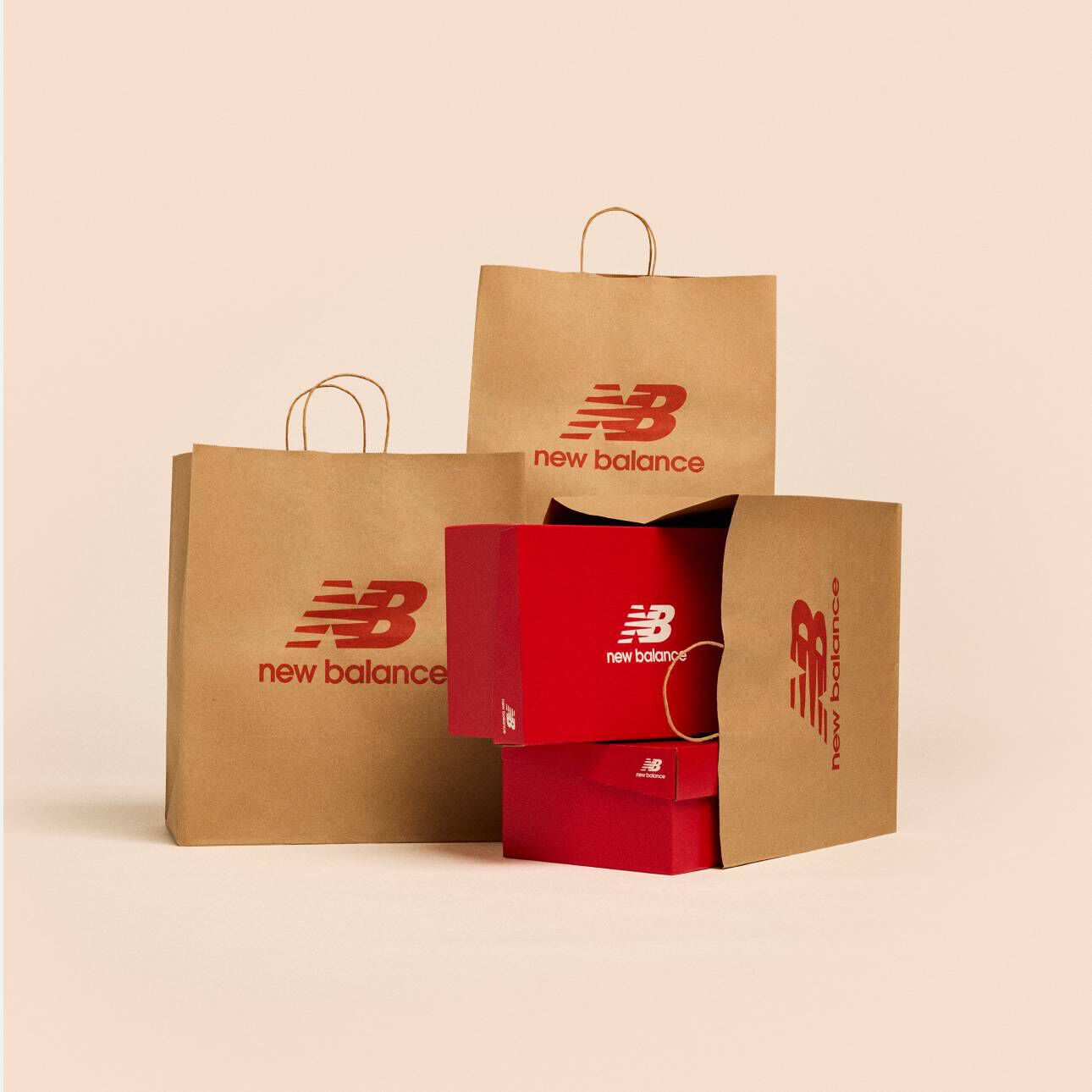 Plusieurs sacs d&rsquo;&eacute;picerie New Balance en papier brun sur un fond de studio beige.